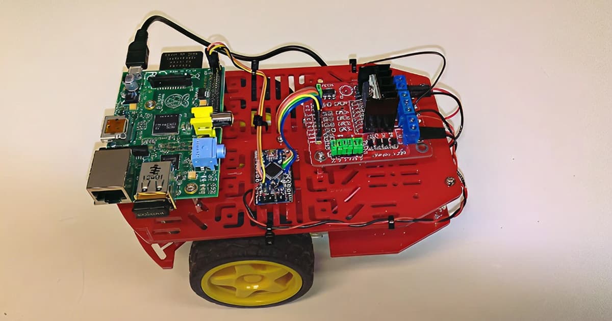 Red two wheel robot chassis with a Raspberry Pi board, motor driver and wiring mounted on top, used for the C3Pi project running Dyalog APL.