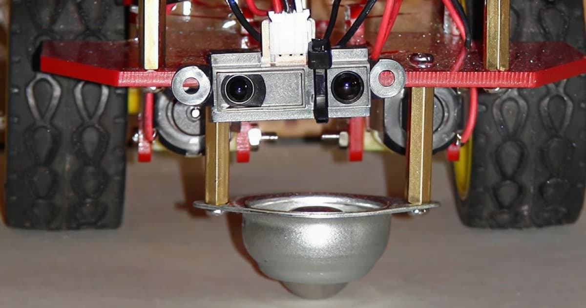 Close-up front view of the C3Pi robot showing a stereo camera module mounted under the red chassis, with wiring, brass standoffs and a front ball caster.