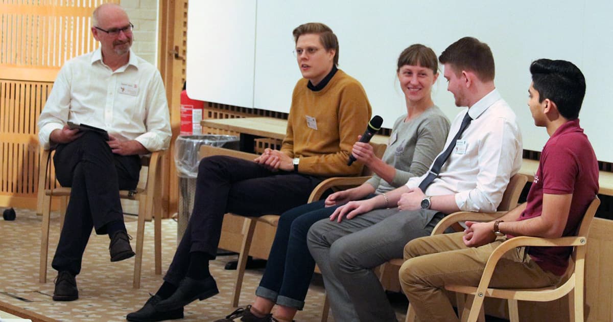 Five people seated in a row on stage for the Young APLers' Panel, including Stephen Taylor, Alve Björk, Yuliia Serhiienko, James Heslip, and Josh David, engaged in a discussion with microphones.