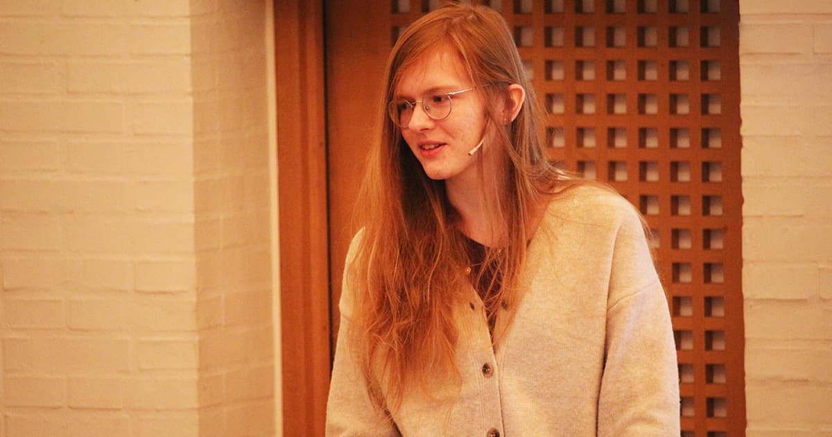 Kamila Szewczyk presenting at Dyalog ’23, speaking at the podium while wearing glasses and a light cardigan.