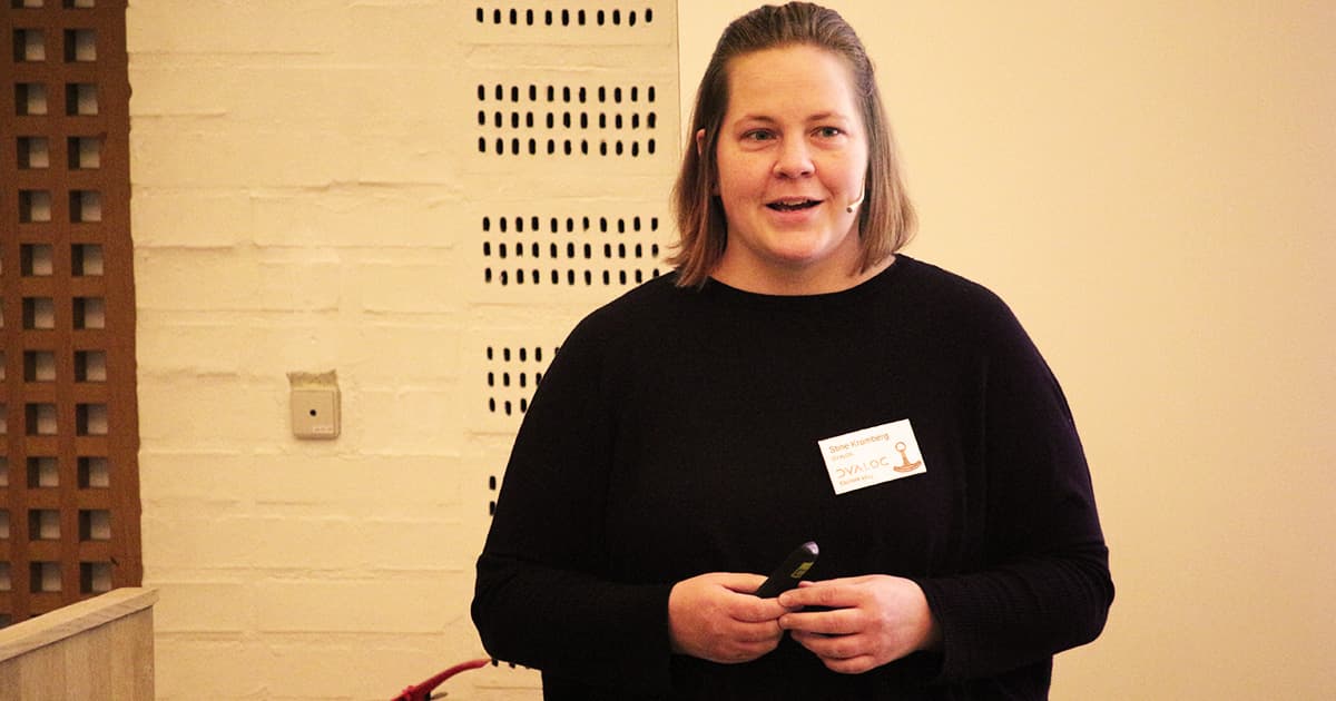Stine Kromberg speaking at Dyalog ’23, holding a presentation remote and wearing a headset microphone.