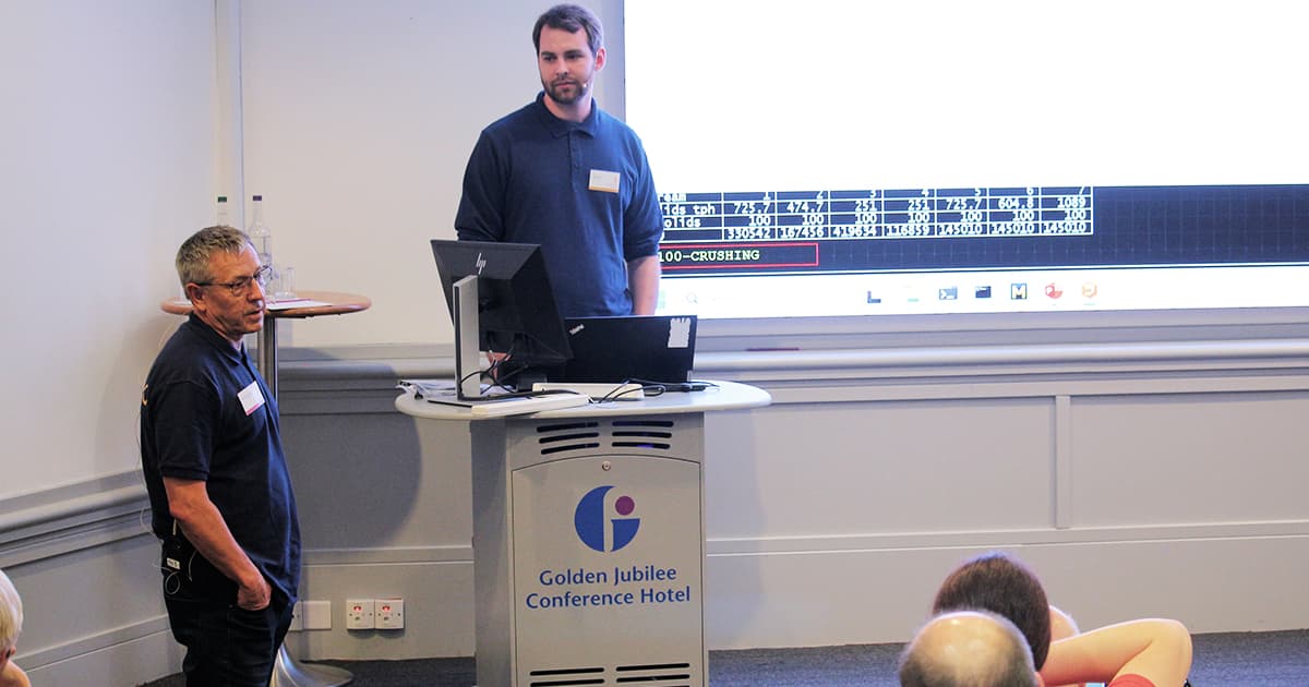 Morten Kromberg and Karl Holt present together at Dyalog ’24, standing by the podium with slides projected on the screen behind them at the Golden Jubilee Conference Hotel.