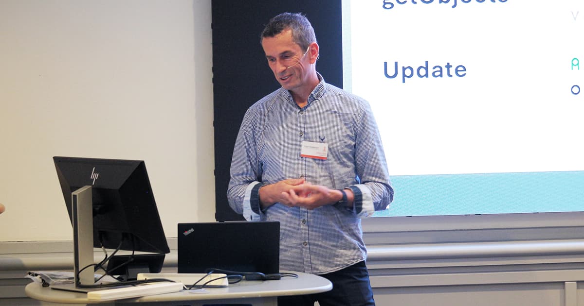 Jürgen Wiedemann presenting at Dyalog ’24 in Glasgow, standing beside a laptop and speaking in front of a projected slide with the word “Update” visible.