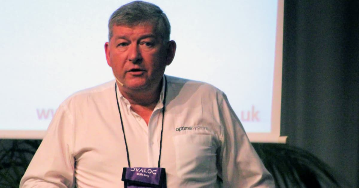 Paul Grosvenor speaking at Dyalog ’15 in Sicily, wearing an Optima Systems shirt and a Dyalog conference badge.