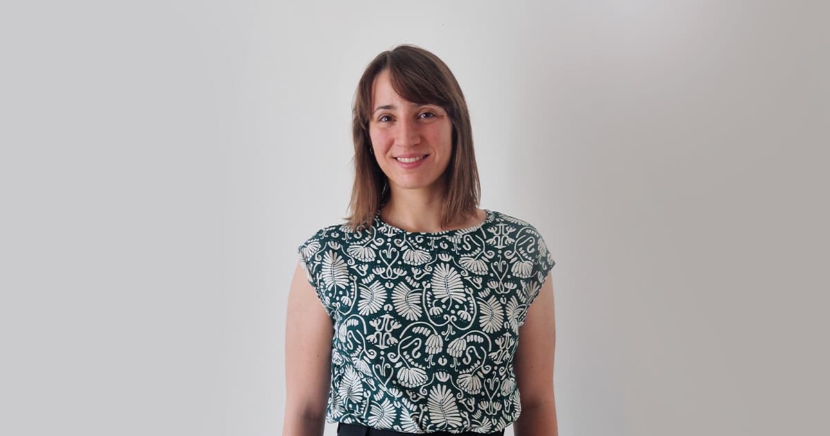 Martina Crippa smiling, wearing a patterned top with a light grey background.