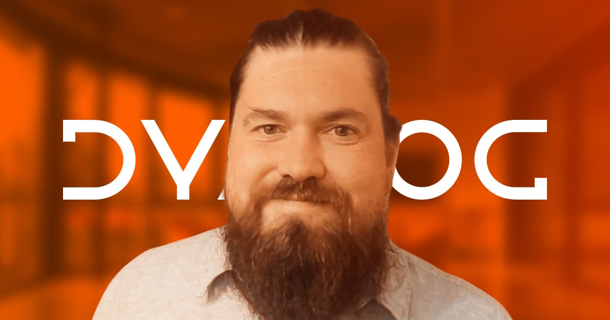 Head-and-shoulders portrait of a bearded man smiling in front of an orange background with the Dyalog wordmark.
