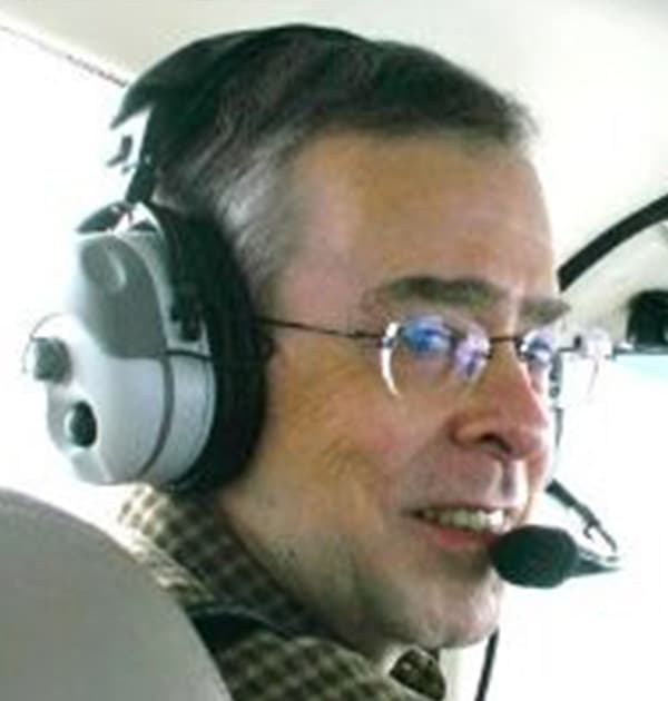 Ron Murray wearing a headset and microphone while seated in an aircraft cockpit.
