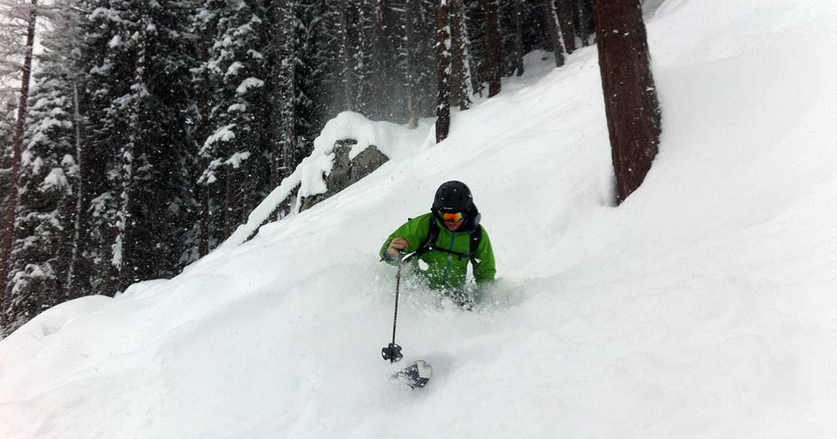 Stefan Kruger skiing through deep powder snow in a forest on a snowy day in Courmayeur, Italy.