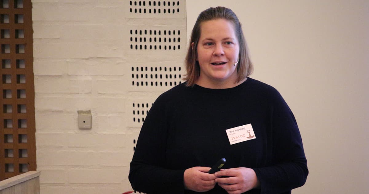 Stine Kromberg speaking during her presentation at Dyalog ’23 in Elsinore, Denmark. She stands at the podium with a microphone headset, addressing the audience.