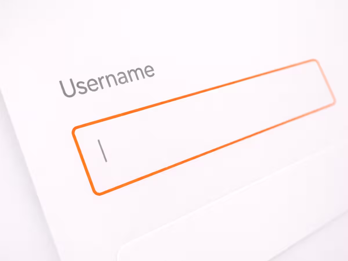 Close-up, angled view of a light mode login interface showing a single “Username” input field outlined in orange, with a blinking text cursor inside and minimalist typography on a soft white background.
