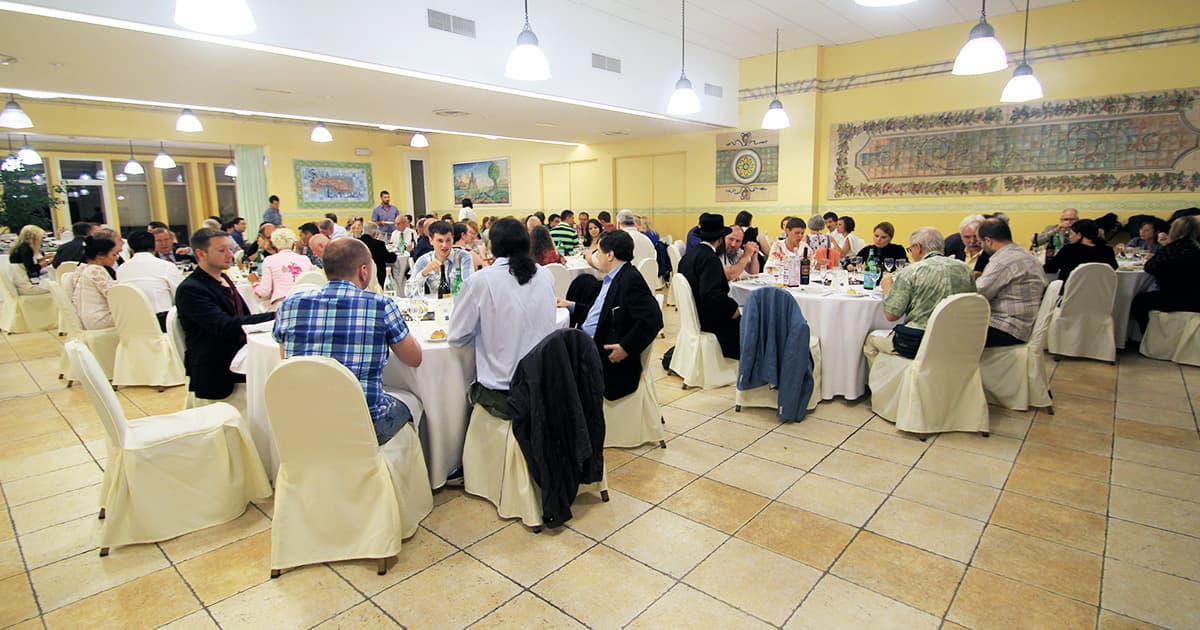 Delegates seated at round tables during a dinner event at Dyalog '15, held at Atahotel Naxos Beach in Sicily, Italy.