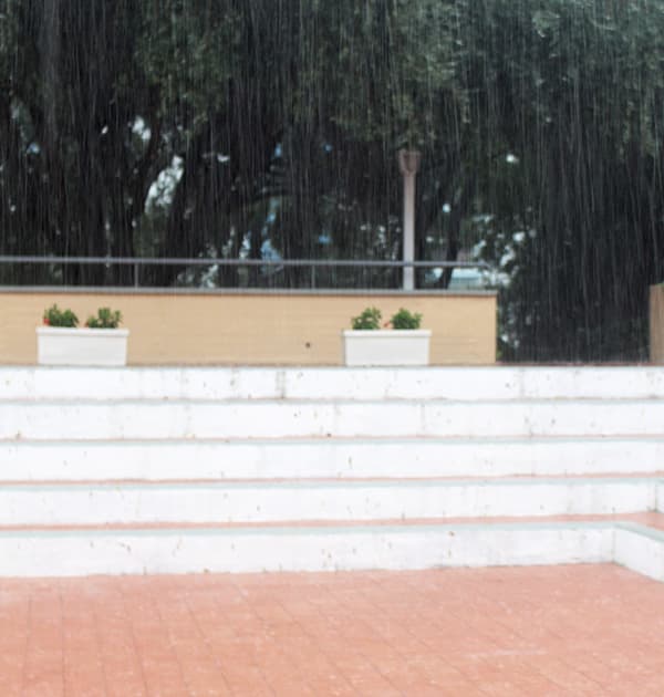 Heavy rain falling on white concrete steps with terracotta tiles in the foreground at Atahotel Naxos Beach during Dyalog '15.